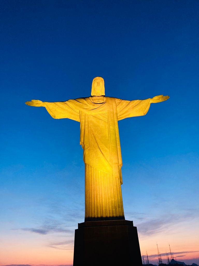Cristo Redentor recebe iluminação em amarelo pelo Dia do Policial Civil, após Missa em Ação de Graças